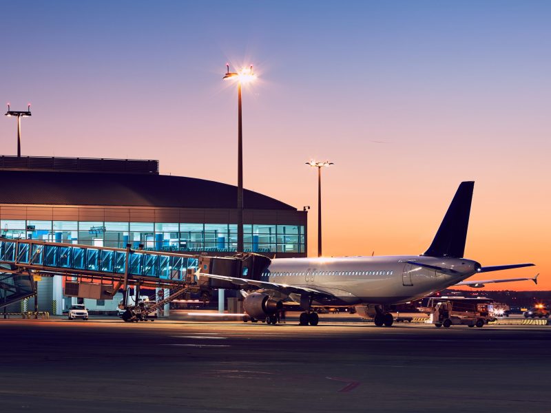 A traveler waits inside Nashville International Airport’s terminal, looking out at planes taking off while their private black car service arrives curbside for a seamless transfer.